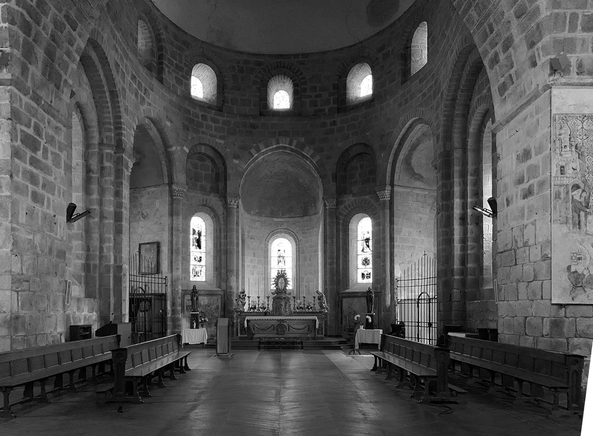 Vue de l'intérieur du chœur de l'abbatiale de Solignac, montrant l'autel éclairé, l'ambon en métal et la structure en pierre romane sous les voûtes.
