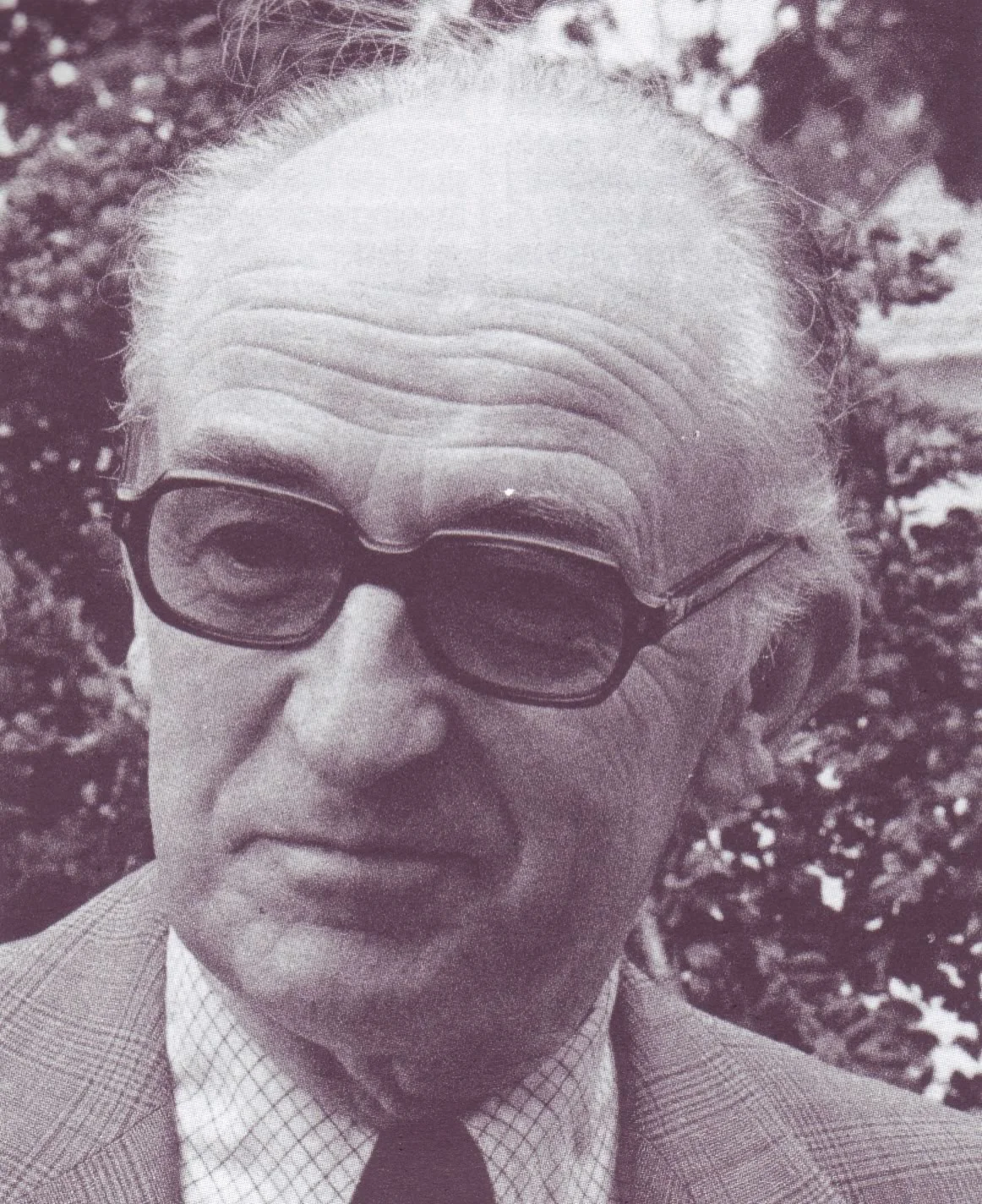 Portrait en noir et blanc de Jean Ousset portant des lunettes de vue et une veste de costume.